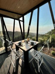 a wooden table and chairs on a deck with a view at Cabaña bosque con Vista Increíble, Tinaja y WiFi in Cobquecura +37 photos