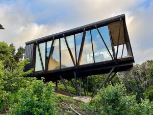 a building with glass windows on top of a hill at Cabaña bosque con Vista Increíble, Tinaja y WiFi in Cobquecura