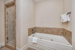 a white bathroom with a tub and a shower at Sea Gate #106 in Demere Park +26 photos