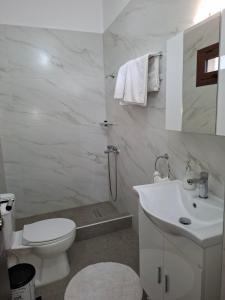 a white bathroom with a toilet and a sink at Guesthouse Athanasiou in Kato Loutraki