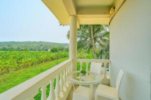 カラングートにあるPhase 369 Casa De Village North Goaの野原の景色を望むバルコニー(テーブル、椅子付)