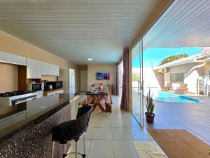 a kitchen and living room with a view of a pool at Casa 2 Suítes + 2 quartos piscina e churrasqueira in Foz do Iguaçu