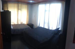 a bedroom with a bed and a window with curtains at Cabaña La Veranera in Paipa