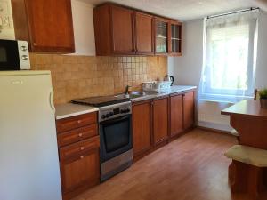 a kitchen with wooden cabinets and a stove top oven at Vitorlásház in Balatonvilágos +20 photos