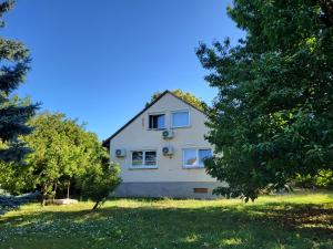 a white house with trees in front of it at Vitorlásház in Balatonvilágos