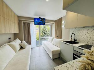 a small living room with a couch and a kitchen at Sea Happens Studio - Palangos Loftai in Palanga
