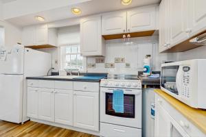 a white kitchen with white cabinets and a microwave at The Genoa in Dennis Port