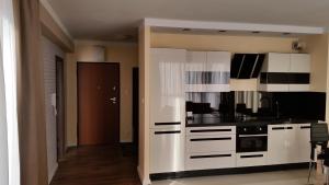 a kitchen with white cabinets and black appliances at Apartament Wilga Park in Krakow