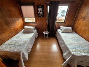 Dos camas en una habitación con paredes de madera. en La Morada del Río, en Valdivia
