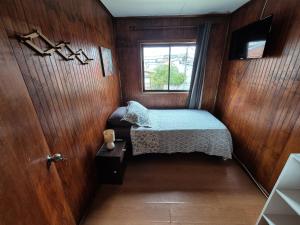 Una pequeña habitación con una cama y una ventana. en La Morada del Río, en Valdivia