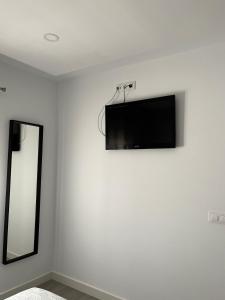 - une télévision à écran plat sur un mur blanc avec un miroir dans l'établissement Family Apartment, à Arcos de la Frontera