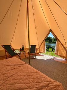 a tent with two chairs and a table and a bed at Lakeside camping in Balninkai