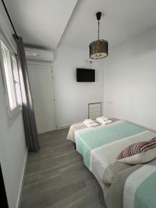 Cette chambre blanche comprend deux lits et une télévision. dans l'établissement Family Apartment, à Arcos de la Frontera