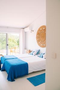 a white bedroom with two beds with blue sheets at Just Like Home - Guarda Rios in Linhares