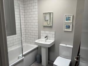 a white bathroom with a sink and a toilet at Causeway Beach House in Portrush +18 photos