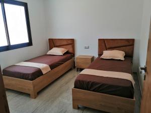 two beds sitting in a room with a window at Les Flots D'ezzahra in Ḩammām al Ghazzāz