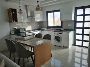 a kitchen with a washing machine and a table and chairs at Les Flots D'ezzahra in Ḩammām al Ghazzāz