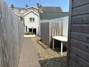 a backyard with a fence and a white bench at Causeway Beach House in Portrush