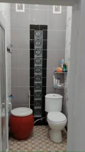 a bathroom with a white toilet and a red tub at Naufal Homestay in Yogyakarta