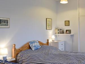 ein Schlafzimmer mit einem Bett mit einer blau-weißen Decke in der Unterkunft Jubilee Cottage in Enstone