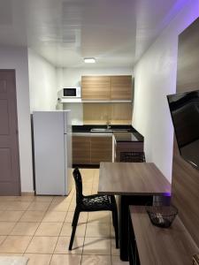 a kitchen with a table and a refrigerator at Cocon Montabo - logement tout équipé avec climatisation et Wi-Fi - à seulement 5 min de la plage in Cayenne