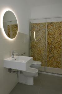 a bathroom with a sink and a toilet and a mirror at Sant Antioco Yellow Apartment with 2 Way Air Con in SantʼAntìoco