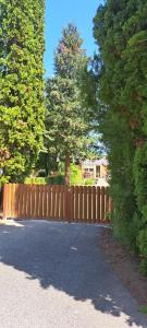a wooden fence in a driveway with a tree behind it at Anna's House in Bük