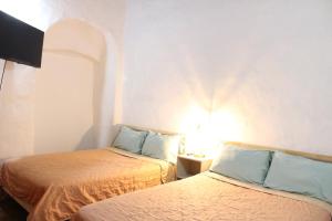 a room with two beds and a lamp on a table at Hospedaje la gran Tenochtitlán in San Martín Hidalgo