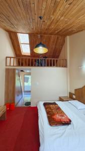 a bedroom with a white bed and a wooden ceiling at Pachamama Hotels- Vashisht in Manāli