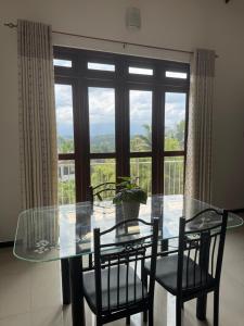 a glass table and chairs in front of a large window at NO 10 Kandy by Kepler & Earth in Kandy