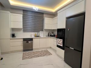eine Küche mit weißen Schränken und einem schwarzen Kühlschrank in der Unterkunft Serentha Villas 2 in Belek