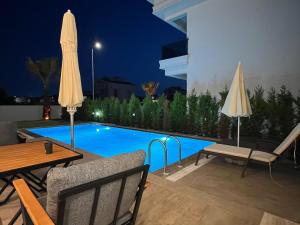 ein Swimmingpool bei Nacht mit Stühlen und Sonnenschirmen in der Unterkunft Serentha Villas 2 in Belek