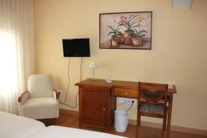 a bedroom with a desk with a chair and a tv at Hotel Villa de Larraga in Larraga