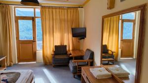 a room with a bed and a desk and a television at Pachamama Hotels- Vashisht in Manāli