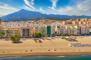 une plage avec des chaises et des parasols en face d'une ville dans l'établissement Estudio Central Beach, à Estepona