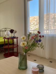 een vaas met bloemen op een tafel met een raam bij Sunset apartment Saronida by the sea with stunning view in Saronida