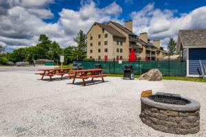 two picnic tables and a fire pit in front of a building at Moose Tracks Lodge - Pool, Hot Tub, Golf, Sauna in Killington
