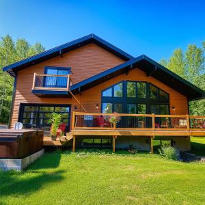 a large wooden house with a large deck at Chalet - Mon toit pour toi ! Bord de lac in Hébertville