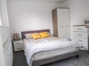 a bedroom with a bed with yellow pillows and a dresser at City breaks Corby Double ensuites in Rockingham