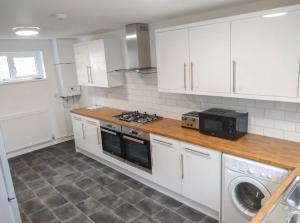 a kitchen with white cabinets and a stove top oven at City breaks Corby Double ensuites in Rockingham +23 photos