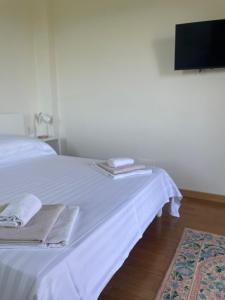 a white bed with towels and a flat screen tv at Villa Andrea in Rodello