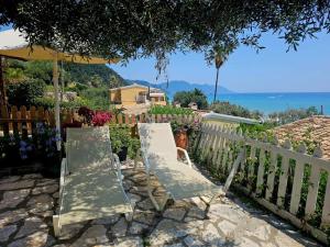 zwei Stühle und ein Regenschirm neben einem Zaun in der Unterkunft Corfu Glyfada Menigos Resort 24 in Pelekas