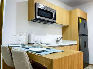 a kitchen with a table with chairs and a microwave at Downtown Playa Studio with Rooftop Pool Steps to Everything in Playa del Carmen