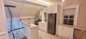 a kitchen with white cabinets and a stainless steel refrigerator at Couchiching Summer Escape in Orillia