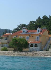 a large house on the shore of the water at Kate Apartments in Kokkari