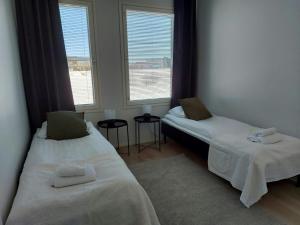 two beds in a room with two windows at Spacious Apartment for 5 with Sauna in Oulu