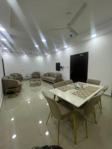 a living room with a table and chairs and a screen at Spacious 2 bedroom & maid room in Jazīrat Umm ash Shajar