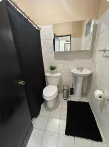 a bathroom with a toilet and a sink and a mirror at Big House Next to the Airport in San Juan