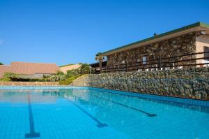 a large swimming pool next to a stone wall at Residence Porto Mannu in Palau