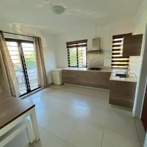 a large kitchen with white tile floors and windows at Sandy Lane Escape - Grand Baie in Grand Baie